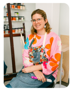 woman in artist smock holding paintbrush
